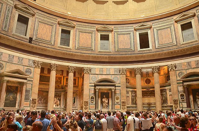 Inside the Pantheon: Corinthian columns, niches with paintings and statues, and a crowd of visitors in the rotunda
